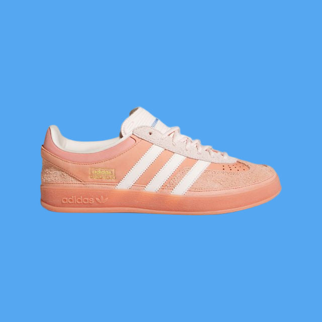 Coral Adidas sneaker with white stripes on a light gray background